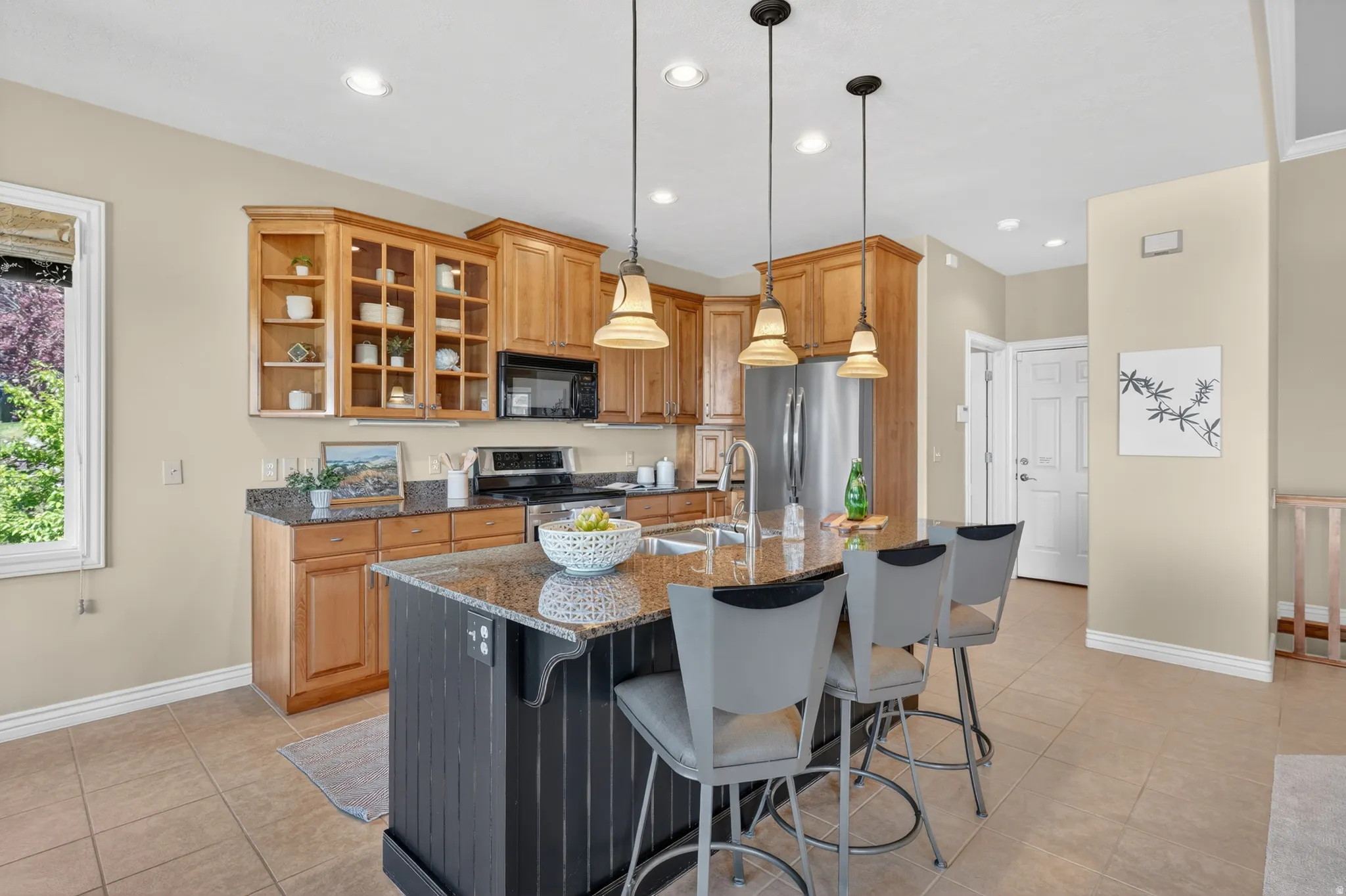 Kitchen featuring a central island with a granite countertop, light wood cabinetry, stainless steel appliances, recessed lighting, and pendant lights
