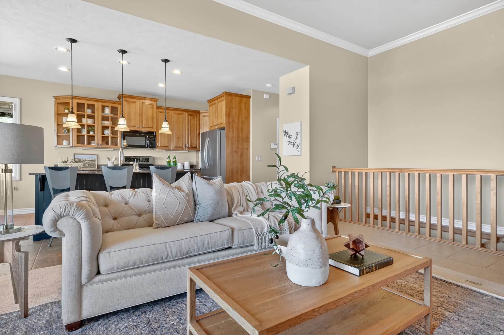 Open-concept living space featuring a kitchen with wood cabinetry, stainless steel appliances, and pendant lighting over a breakfast bar