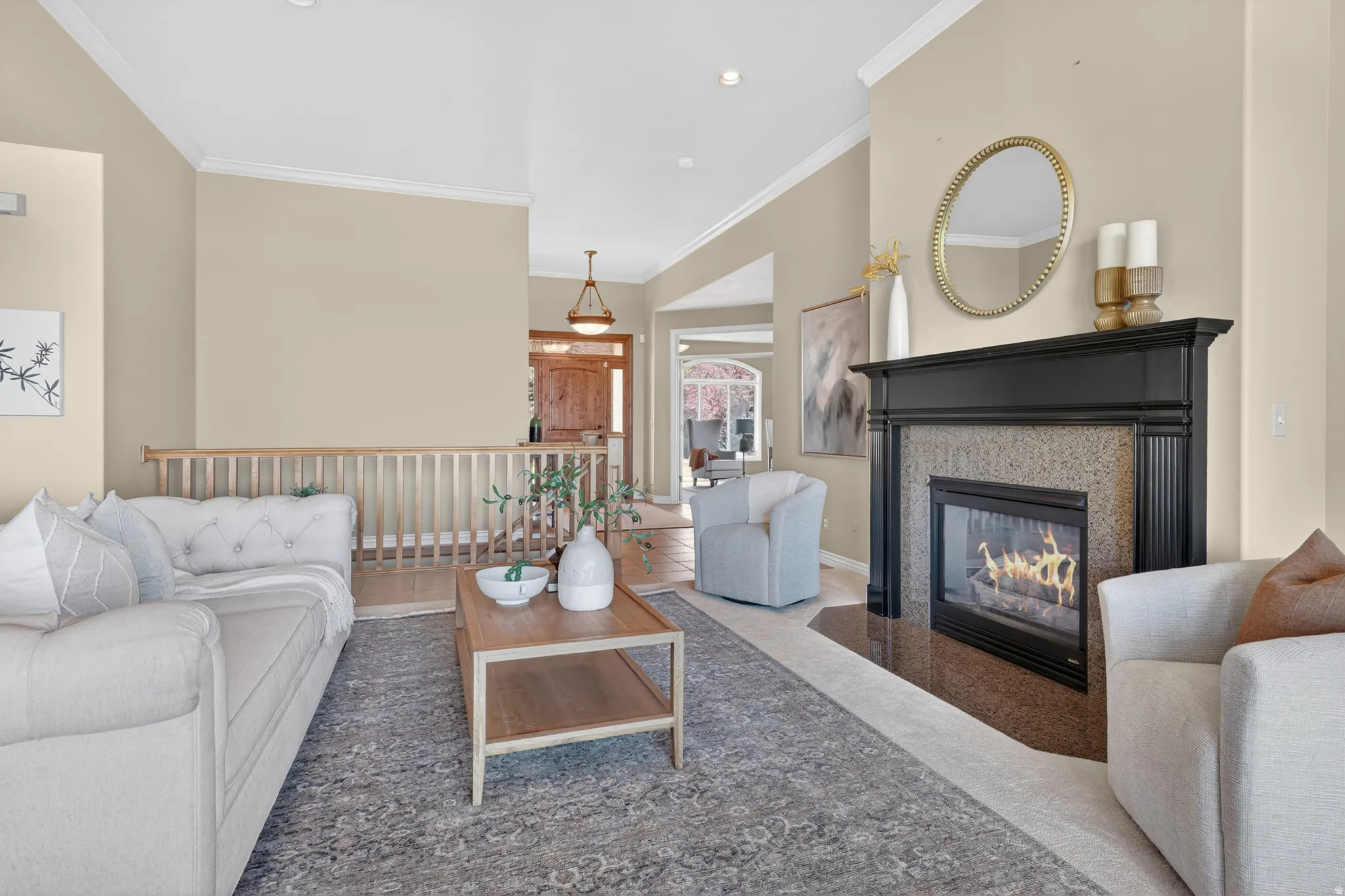 Living area featuring a fireplace with a black mantel and stone surround, wood-finish flooring, a light-toned wood banister, and 10 ft. ceilings