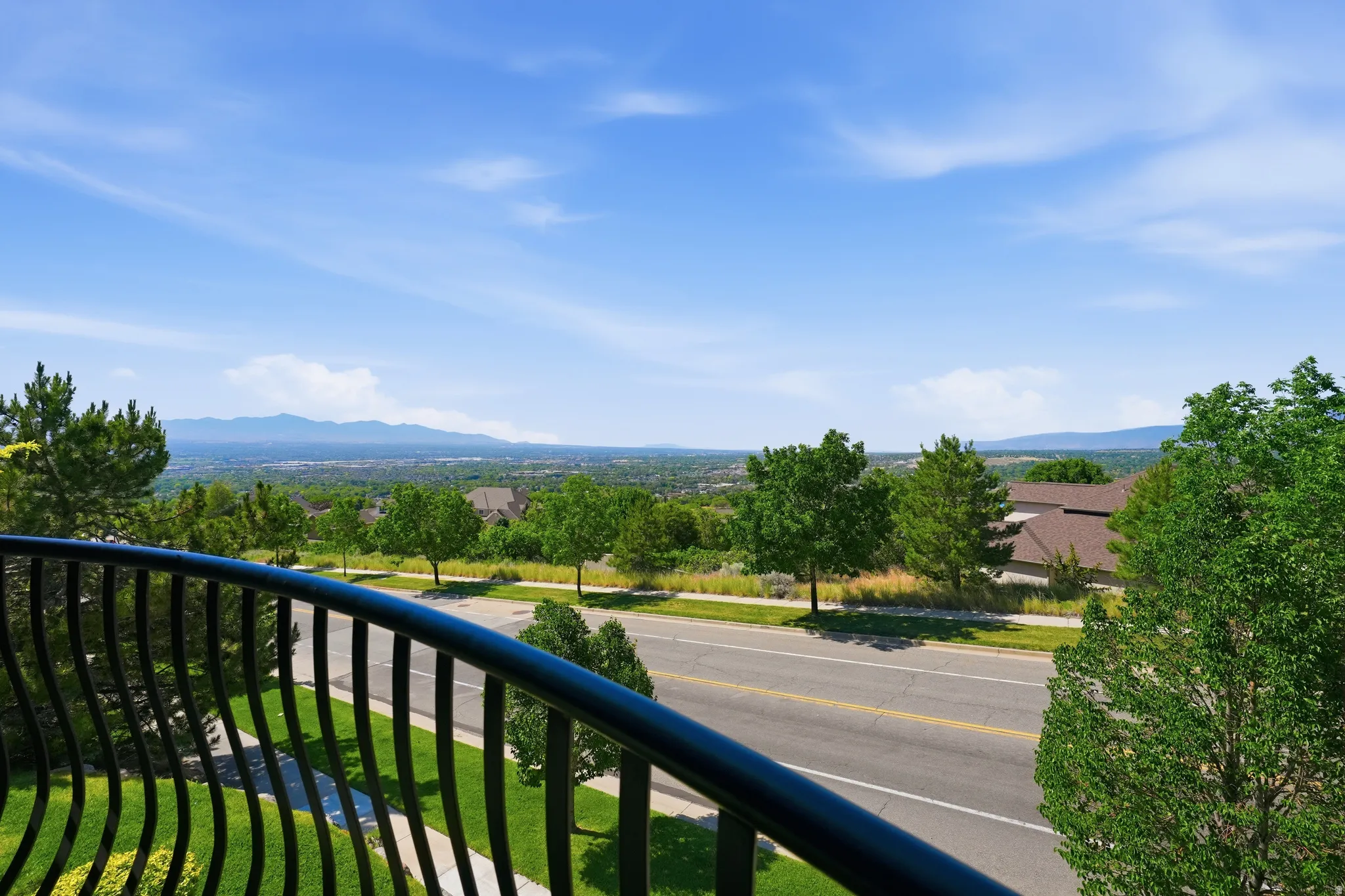 Wrought iron balcony railing overlooking a distant mountain range and expansive tree-lined landscape valley and mountain views
