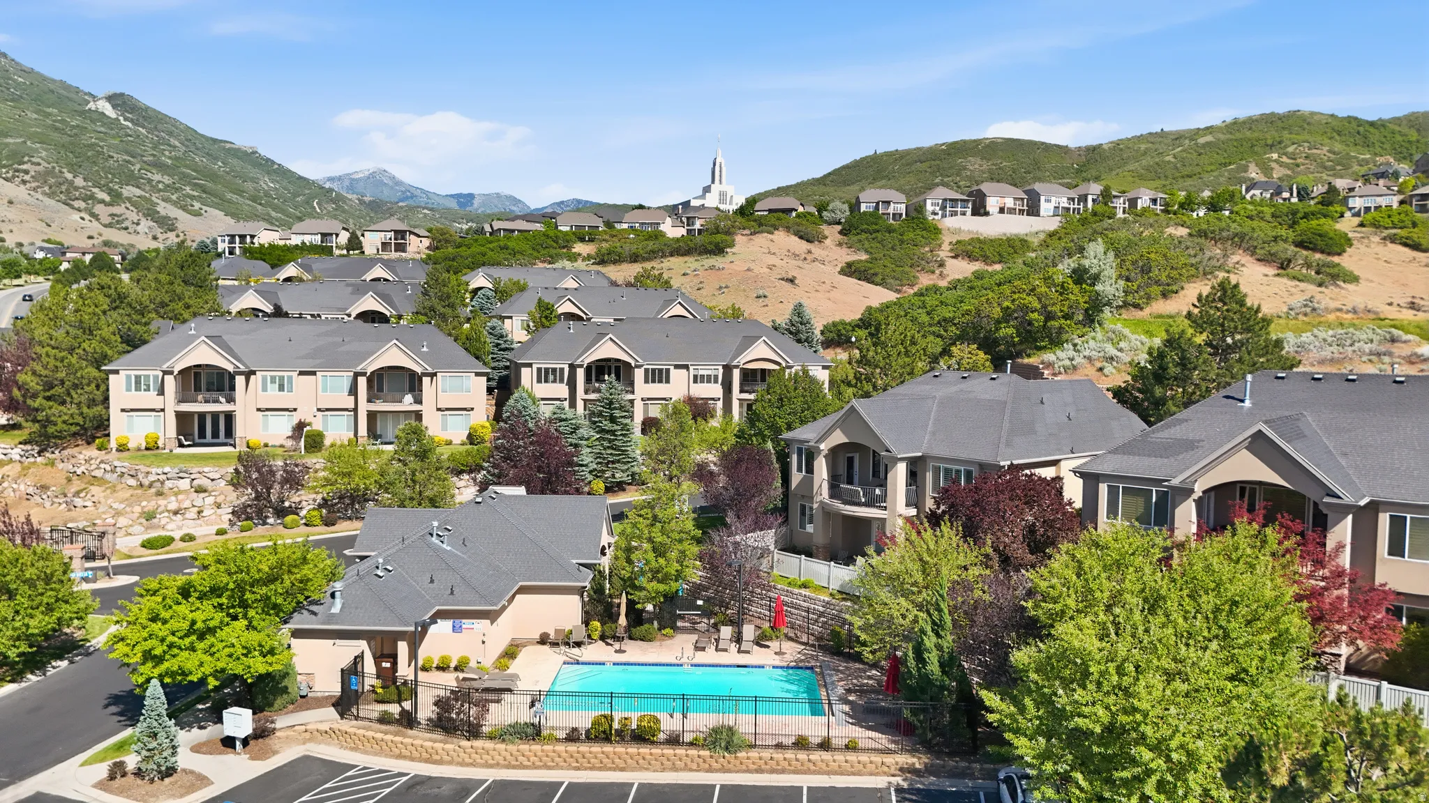 Residential community featuring multi-story buildings with balconies, a communal outdoor swimming pool, and dedicated parking areas