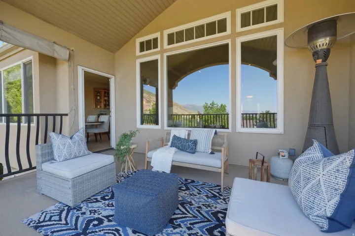 Covered patio space off of kitchen and living room featuring a vaulted ceiling and stucco exterior with mountain and valley views