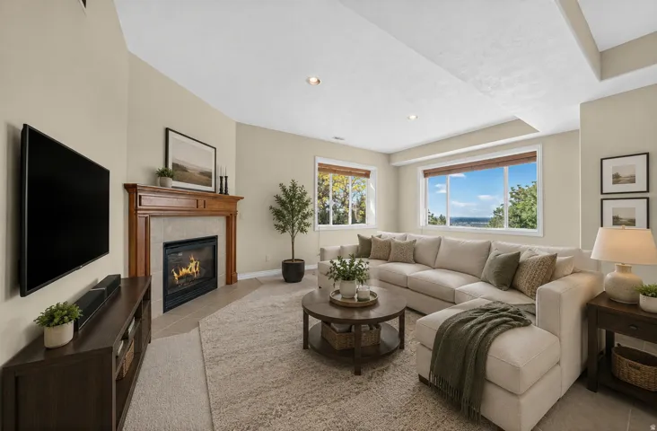 Spacious living area featuring a traditional fireplace with wood mantel and tile surround, recessed lighting, and multiple large windows