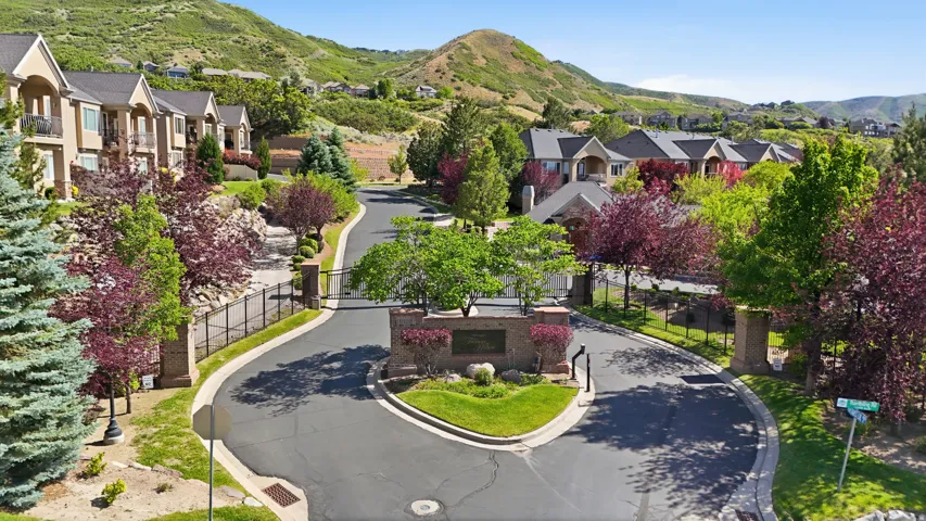 Entrance featuring stone pillars, decorative iron gates, and mature landscaping