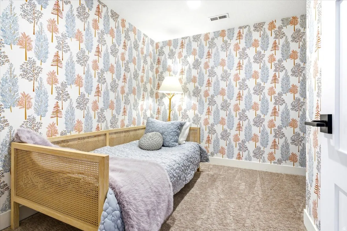 Carpeted room with patterned wall covering, white trim, and a white door with a matte black lever handle
