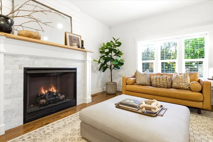 Living area featuring a fireplace with a light-toned stone surround, a white mantel, and a natural wood-finish top