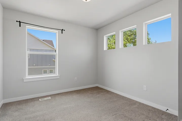 Room featuring a large window, three transom windows, light gray walls, white baseboards, and carpet flooring