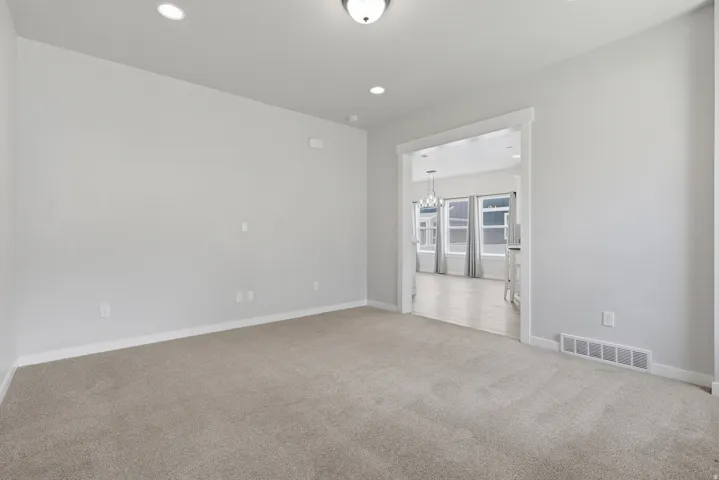 Carpeted interior space featuring recessed lighting, a ceiling-mounted light fixture, and white baseboards