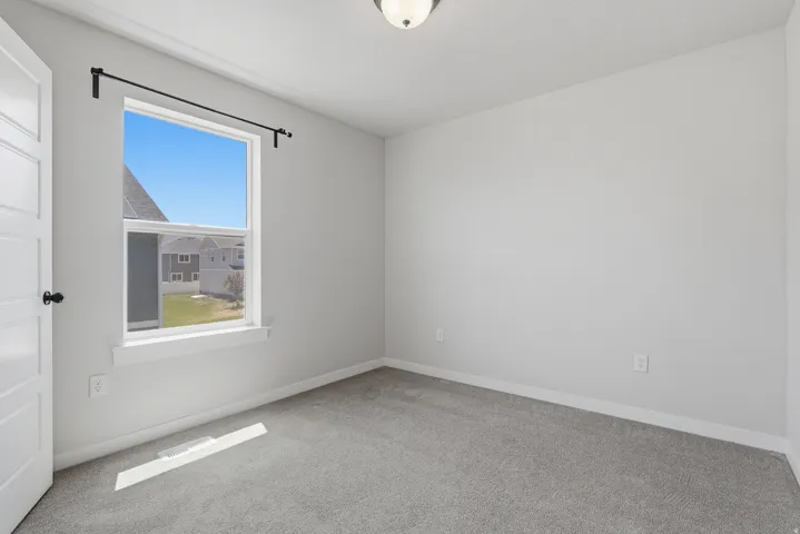 Room featuring a single window with a black curtain rod, light gray wall paint, white trim, gray carpet, and a ceiling-mounted light fixture
