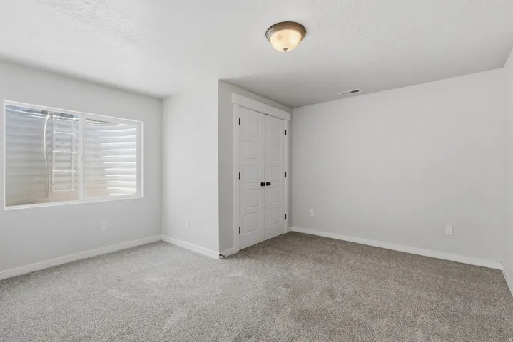 Neutral-toned room featuring a large egress window with a white frame, light gray carpet, and white baseboards
