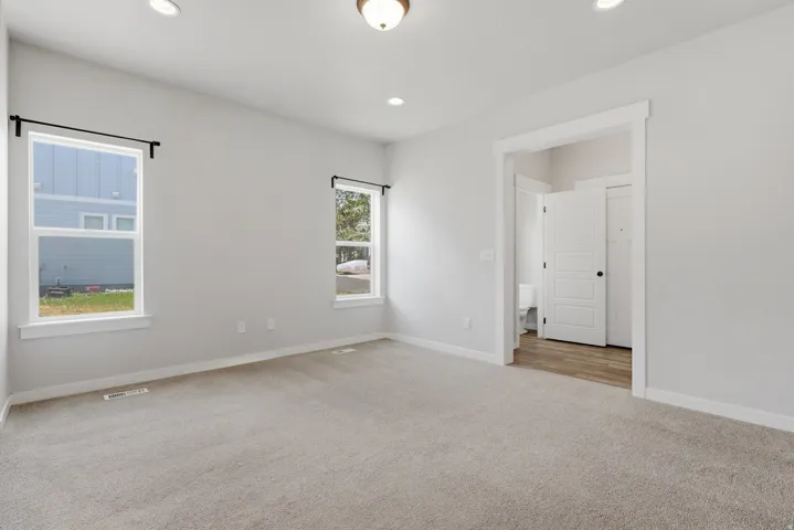 Carpeted room featuring two white-framed windows, recessed lighting, and a central ceiling light fixture