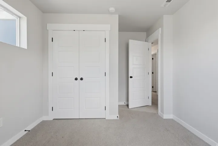 Neutral-toned room featuring a window, light gray carpeting, crisp white walls, and white trim