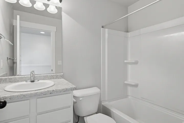 Bathroom featuring a white vanity with a speckled countertop, undermount sink, and chrome faucet