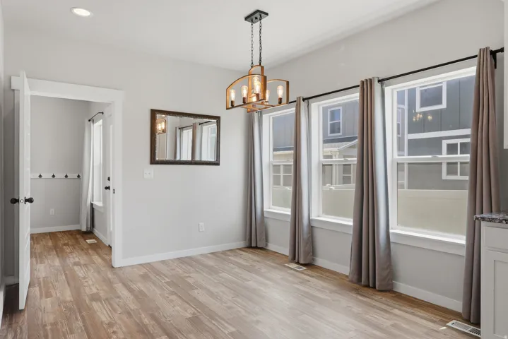 Dining area with wood-finish flooring, recessed lighting, and a linear chandelier
