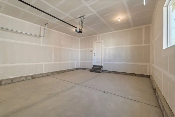 Spacious garage featuring a concrete floor, interior access door with steps, and a single window for natural light
