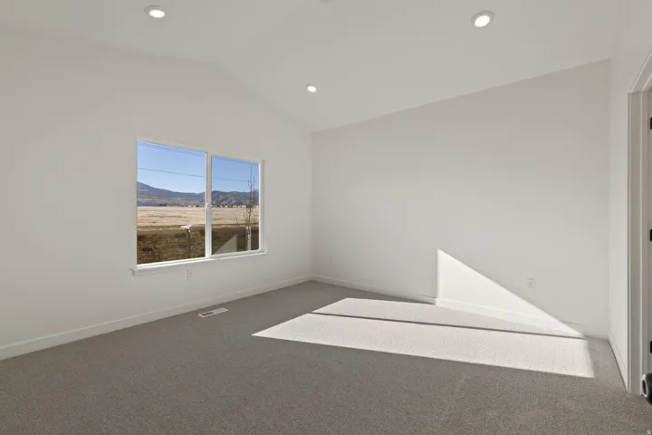 Spacious room featuring vaulted ceilings, recessed lighting, and grey carpet flooring