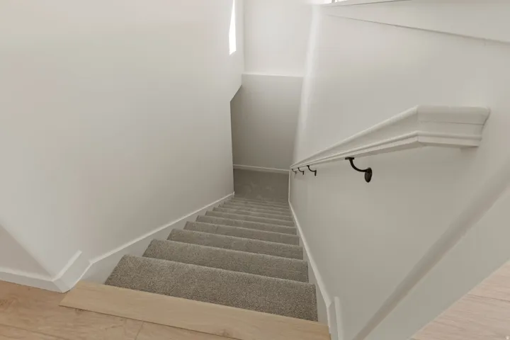 Carpeted stairway with a decorative handrail featuring black brackets
