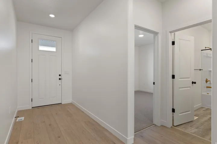 Entry foyer featuring wood-finish flooring, white paneled doors, and recessed lighting