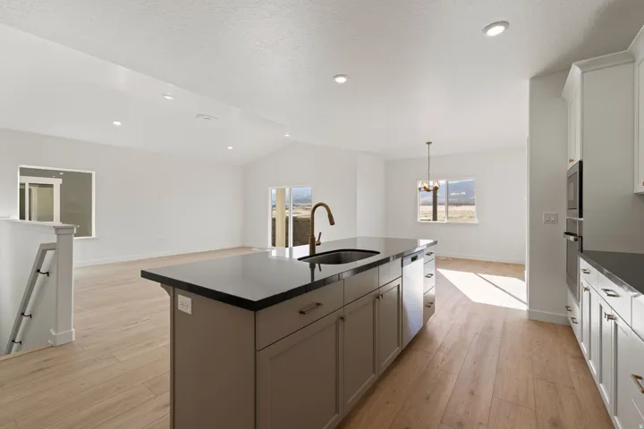 Kitchen island featuring a dark countertop, undermount sink with gooseneck faucet, and integrated cabinetry