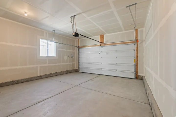 Spacious garage featuring a concrete floor, overhead lighting, and a single window