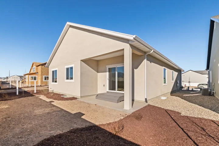Rear exterior featuring a covered patio, sliding glass door, and stucco siding