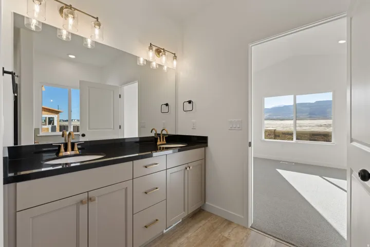 Double vanity featuring a dark countertop, undermount sinks, and brushed gold fixtures