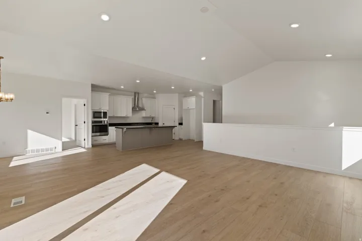 Spacious interior featuring wood-finish flooring, vaulted ceilings, and recessed lighting