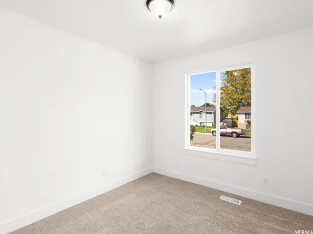 Room featuring neutral carpeting, white painted walls, a white trim package, and a double-paned window