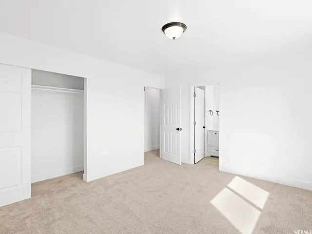 Neutral-toned carpeting extends throughout this room, featuring a closet with sliding doors and an adjacent open doorway
