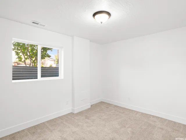 Neutral-toned carpet flooring, white painted walls, and a visible window