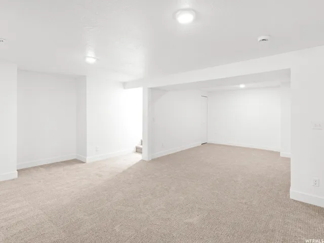 Spacious room featuring neutral carpeting, white walls, and recessed lighting