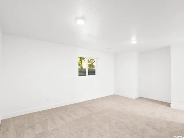 Room featuring soft neutral carpeting, white painted walls, and a window with horizontal blinds