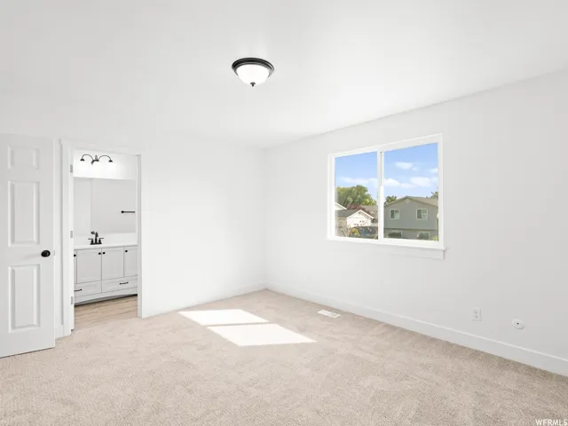 Bright room featuring neutral carpeting, white walls, and a contemporary ceiling light fixture
