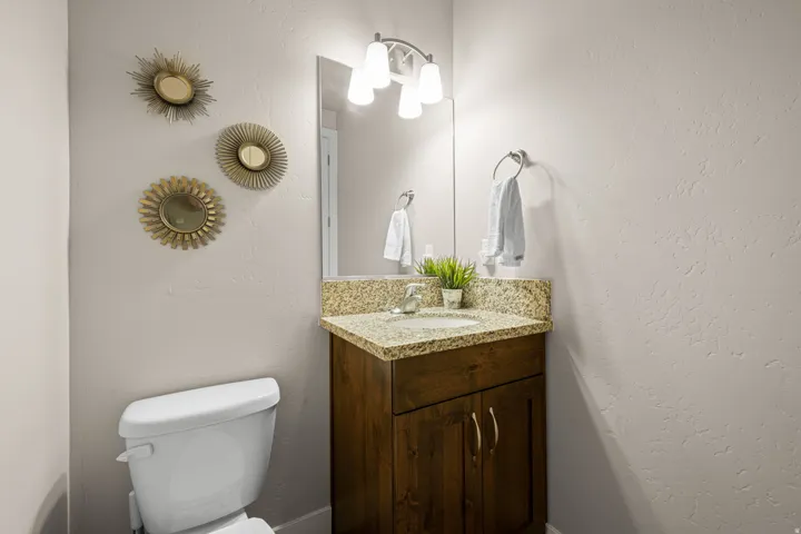Bathroom featuring a granite-look countertop, undermount sink, and wood-finish vanity with cabinet storage
