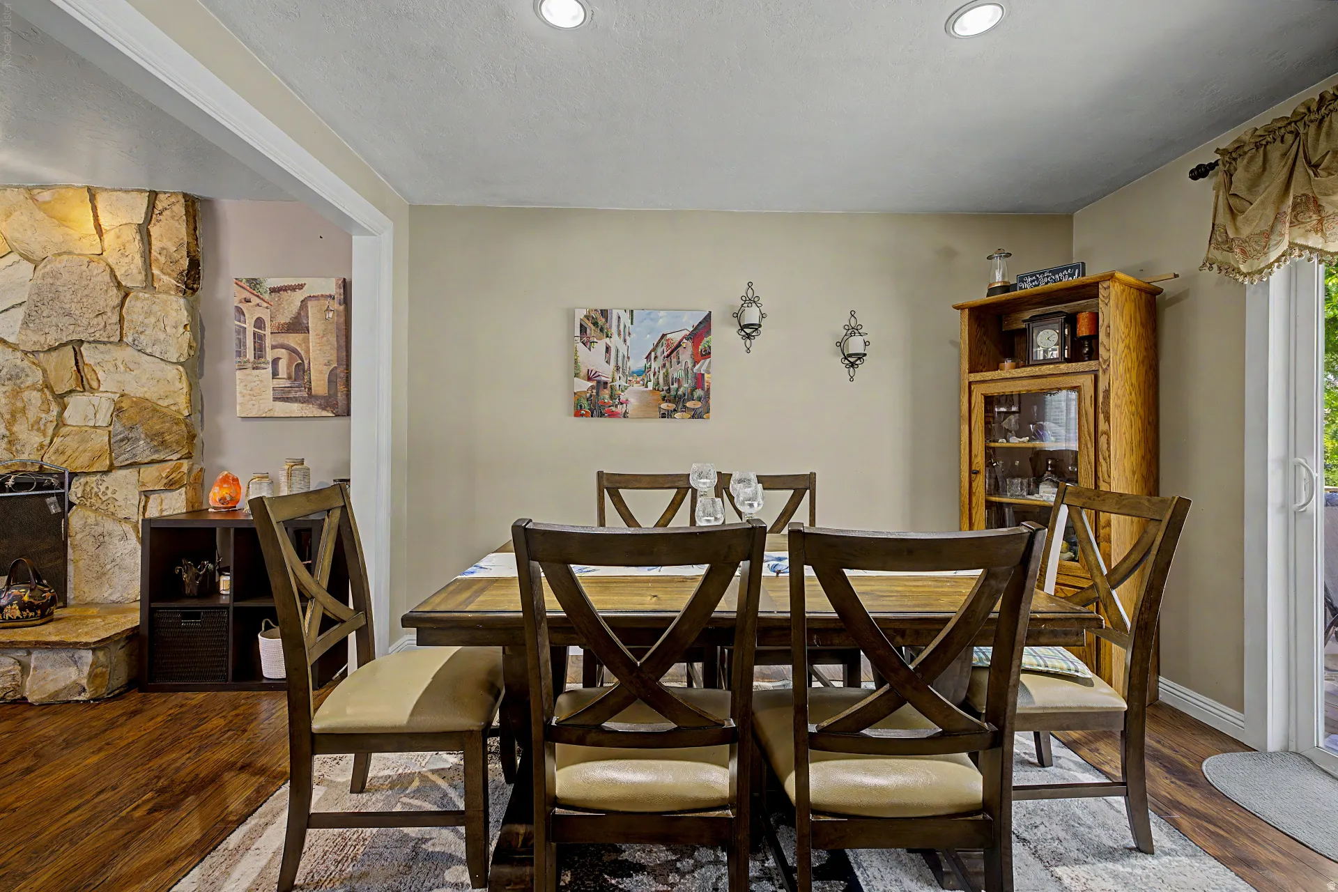 Dining area featuring recessed lighting, a stone fireplace surround, wood-finish flooring, and a sliding glass door