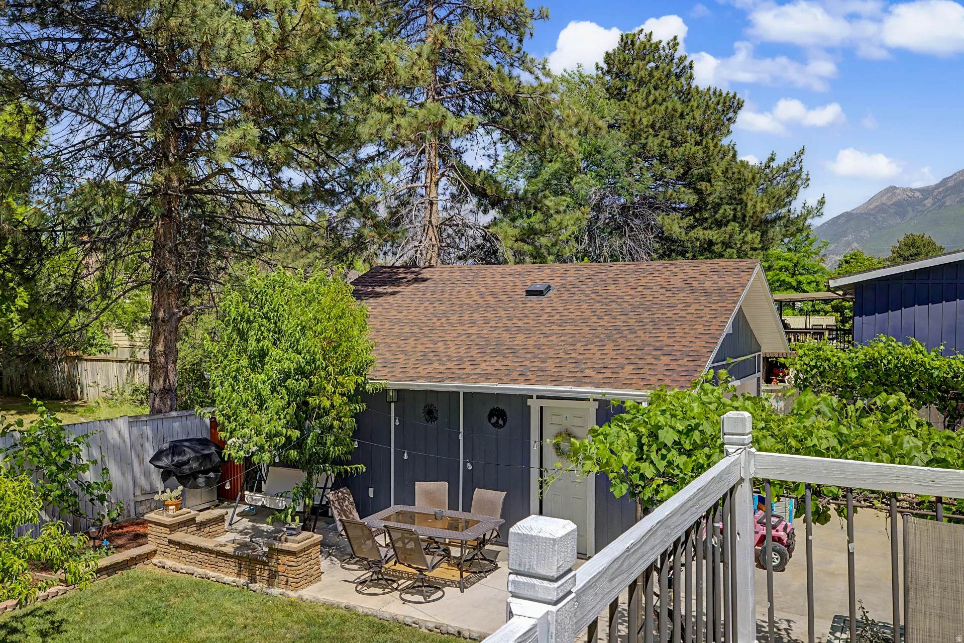 Backyard patio featuring a built-in fire pit with stone surround, concrete paver surface, and fencing