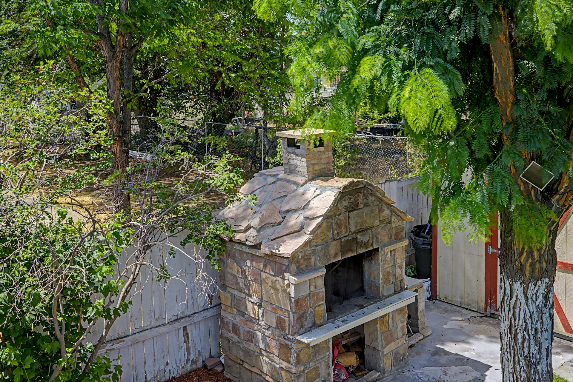 Outdoor stone-built oven with a natural stone chimney and stone-tiled roof