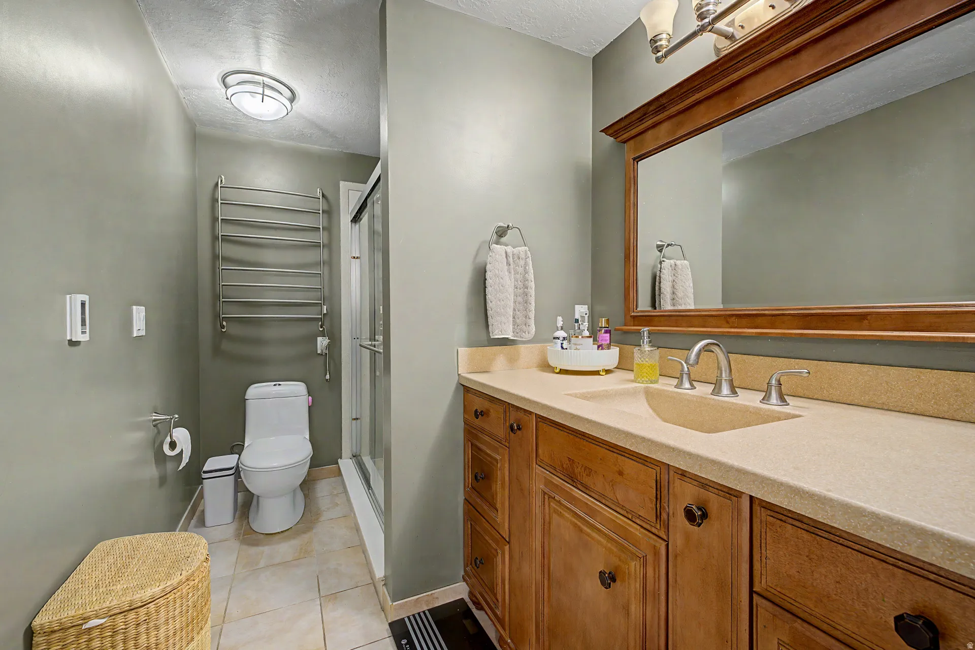 Bathroom featuring a wood-finish vanity with an integrated countertop and sink, framed mirror, and a glass-enclosed shower
