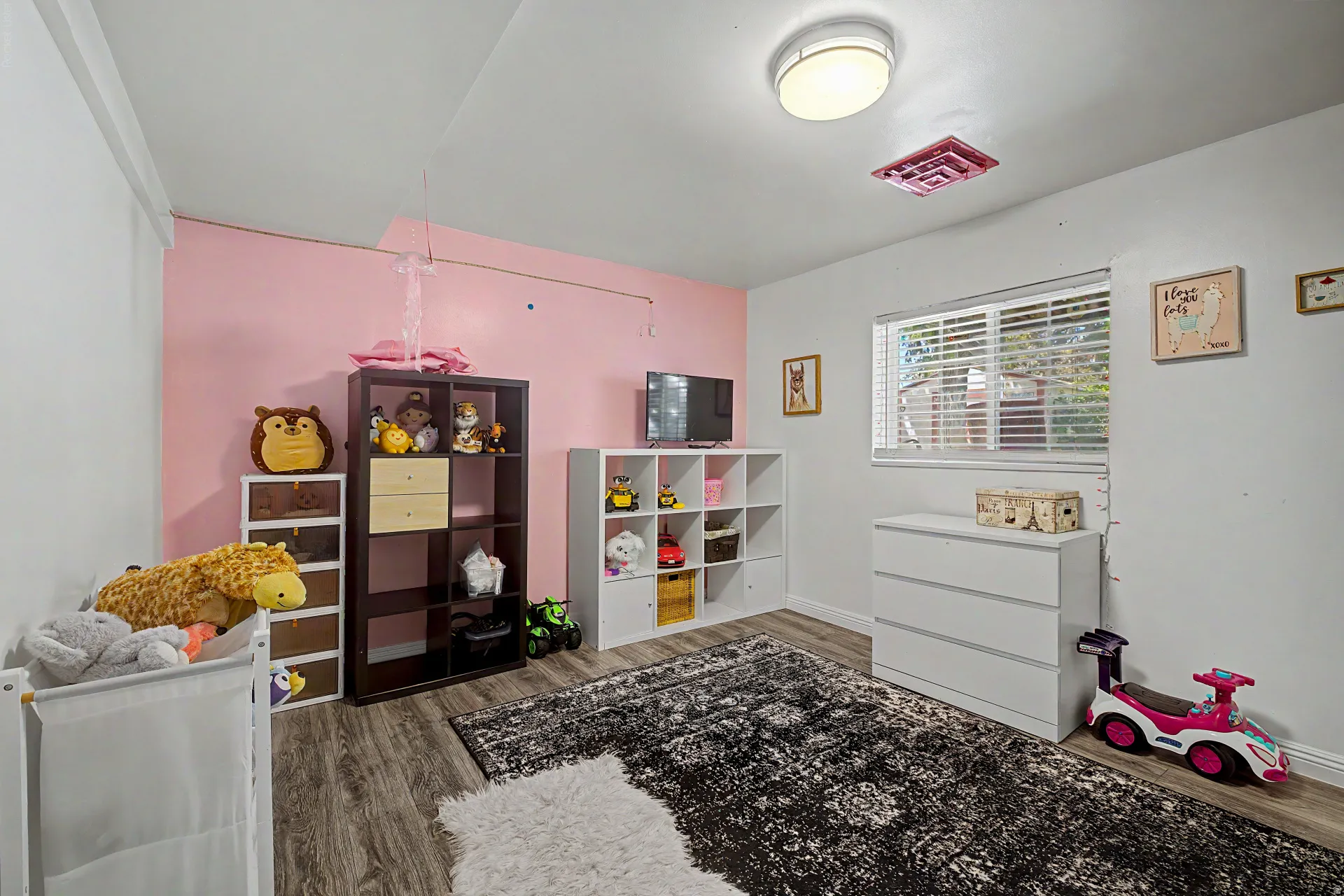 Interior room featuring wood-finish flooring, a flush-mount ceiling light, and a window with horizontal blinds