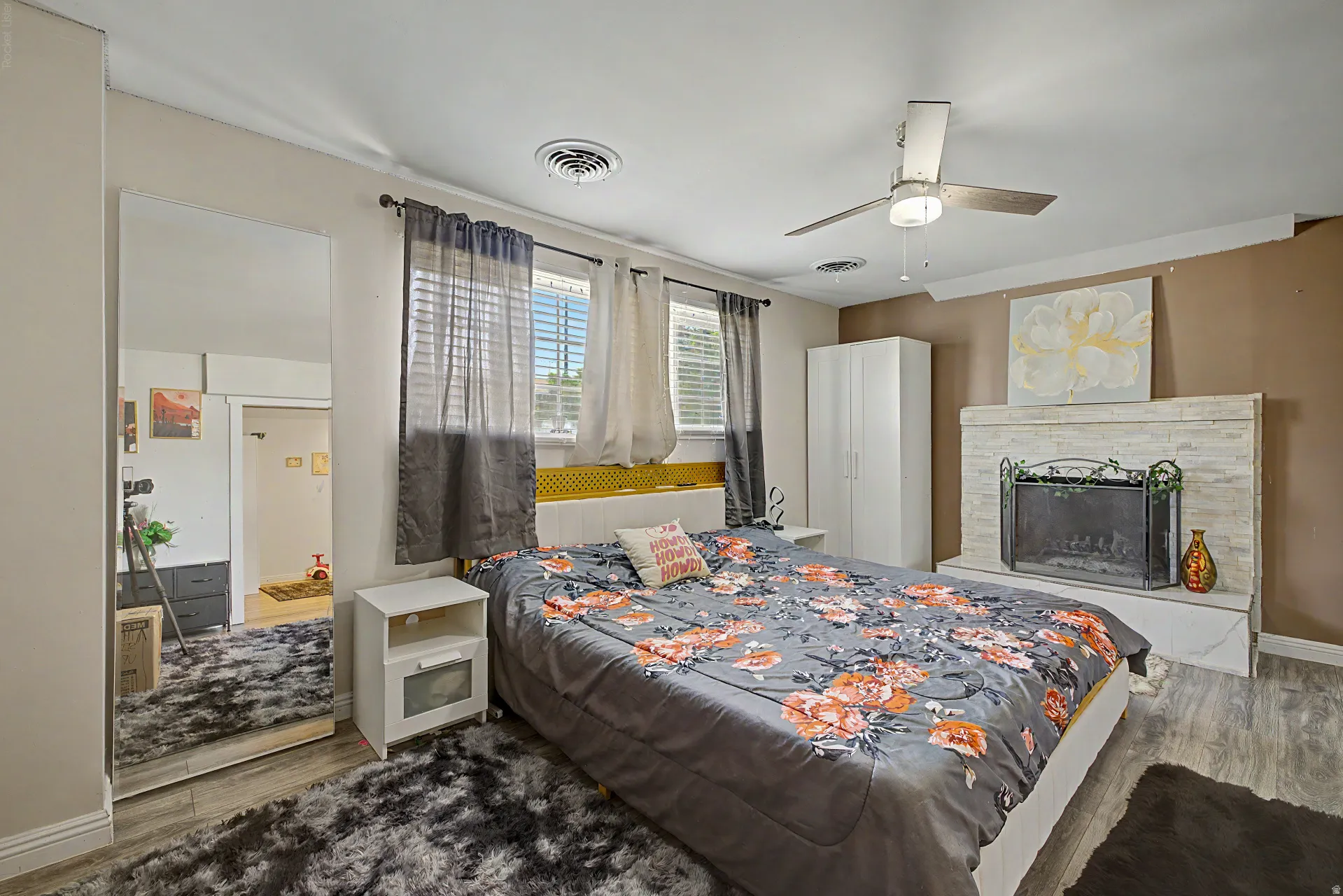 Bedroom featuring a fireplace with a stone-clad surround, a ceiling fan, and wood-finish flooring