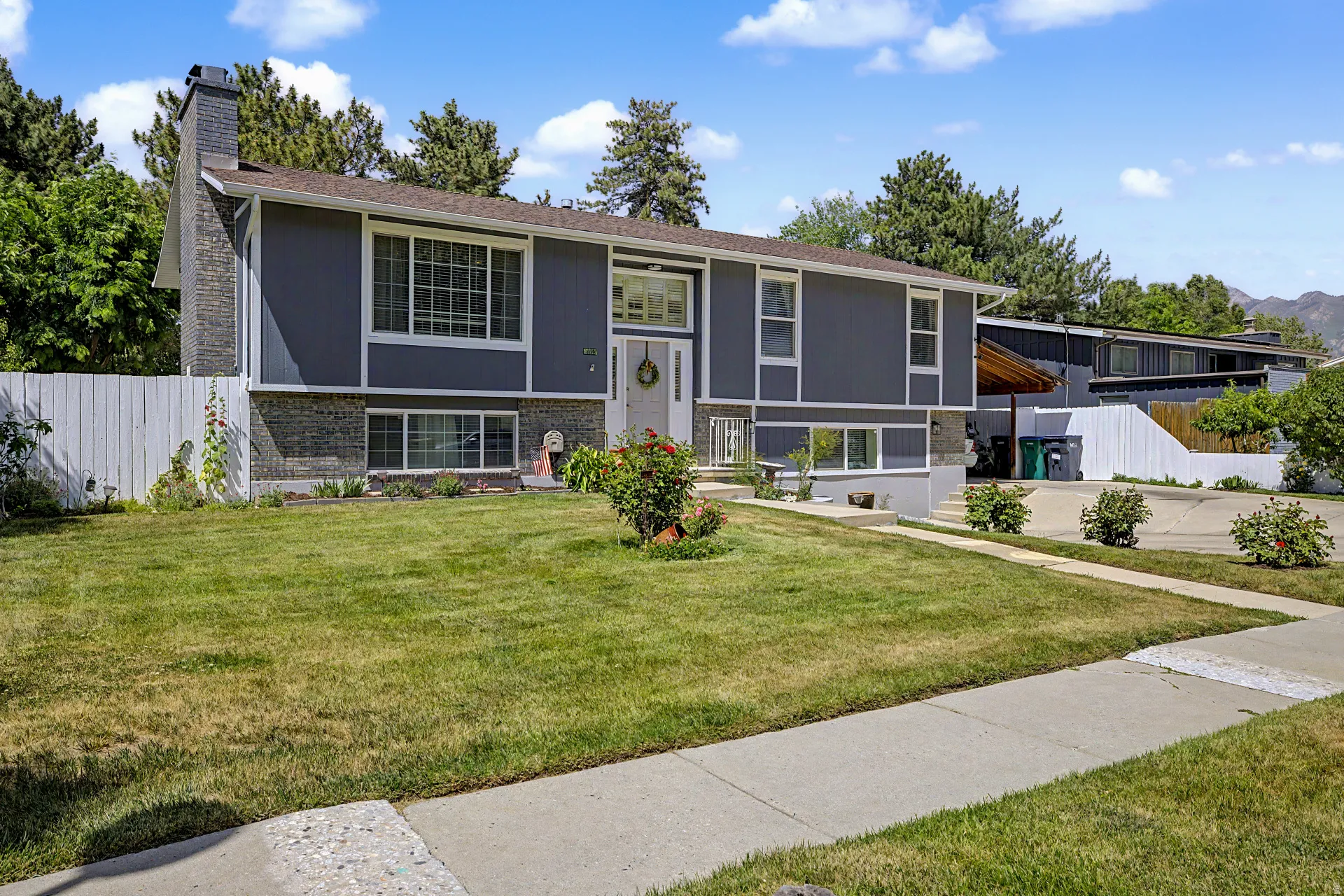 Split-level residence featuring a gray exterior with white trim