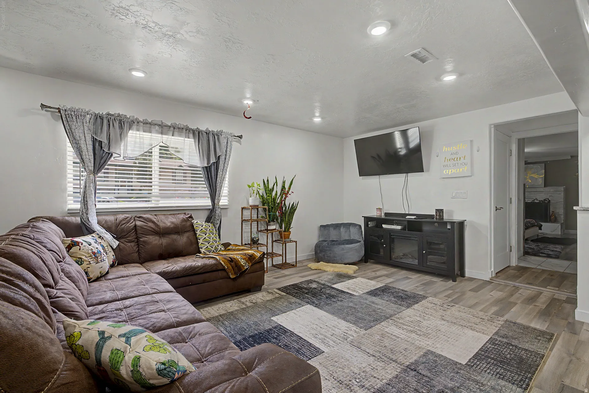 Living area featuring wood-finish flooring, recessed lighting, and a window with blinds