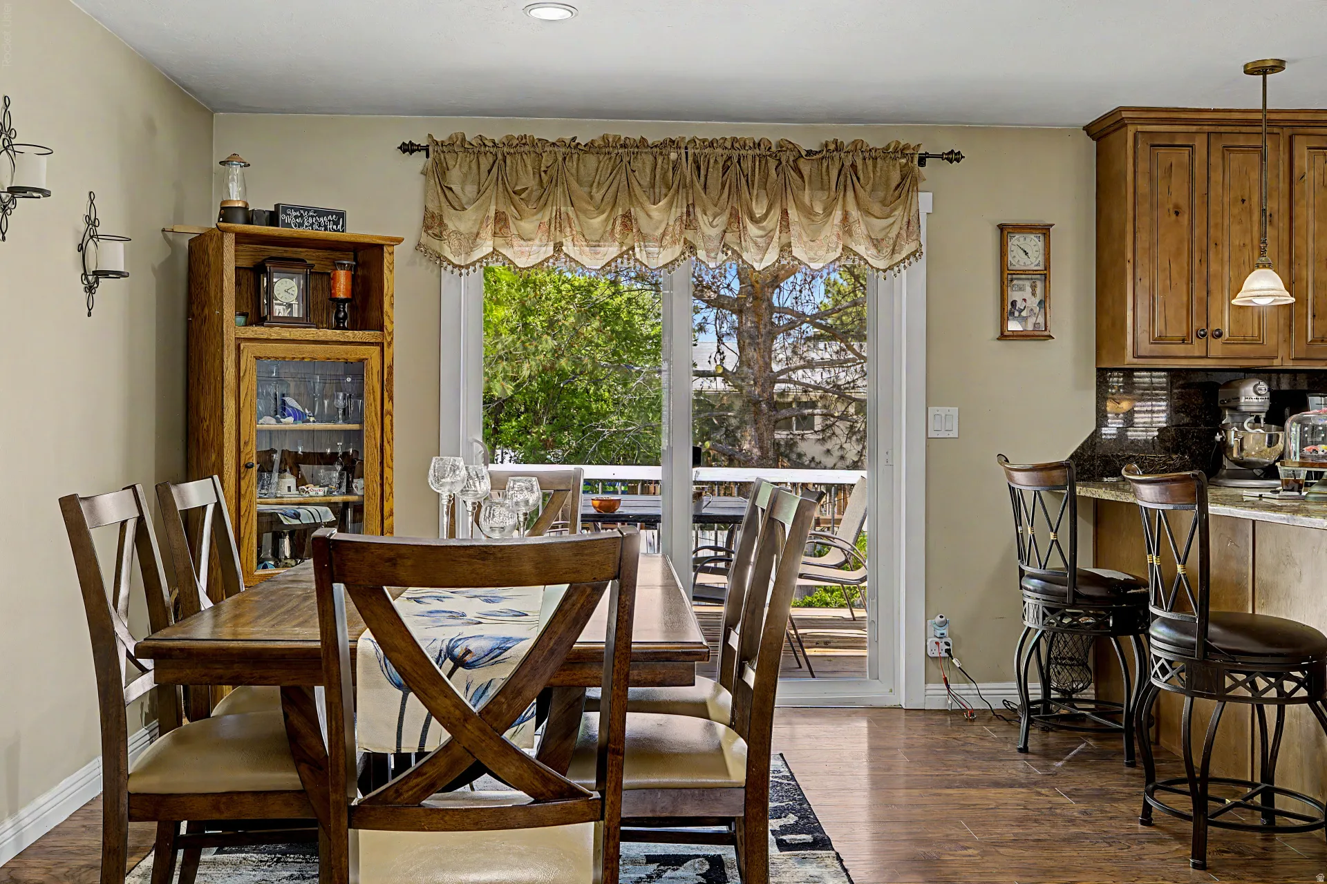 Dining area featuring wood-finish flooring, a glass-front display cabinet, and a sliding glass door to an outdoor deck
