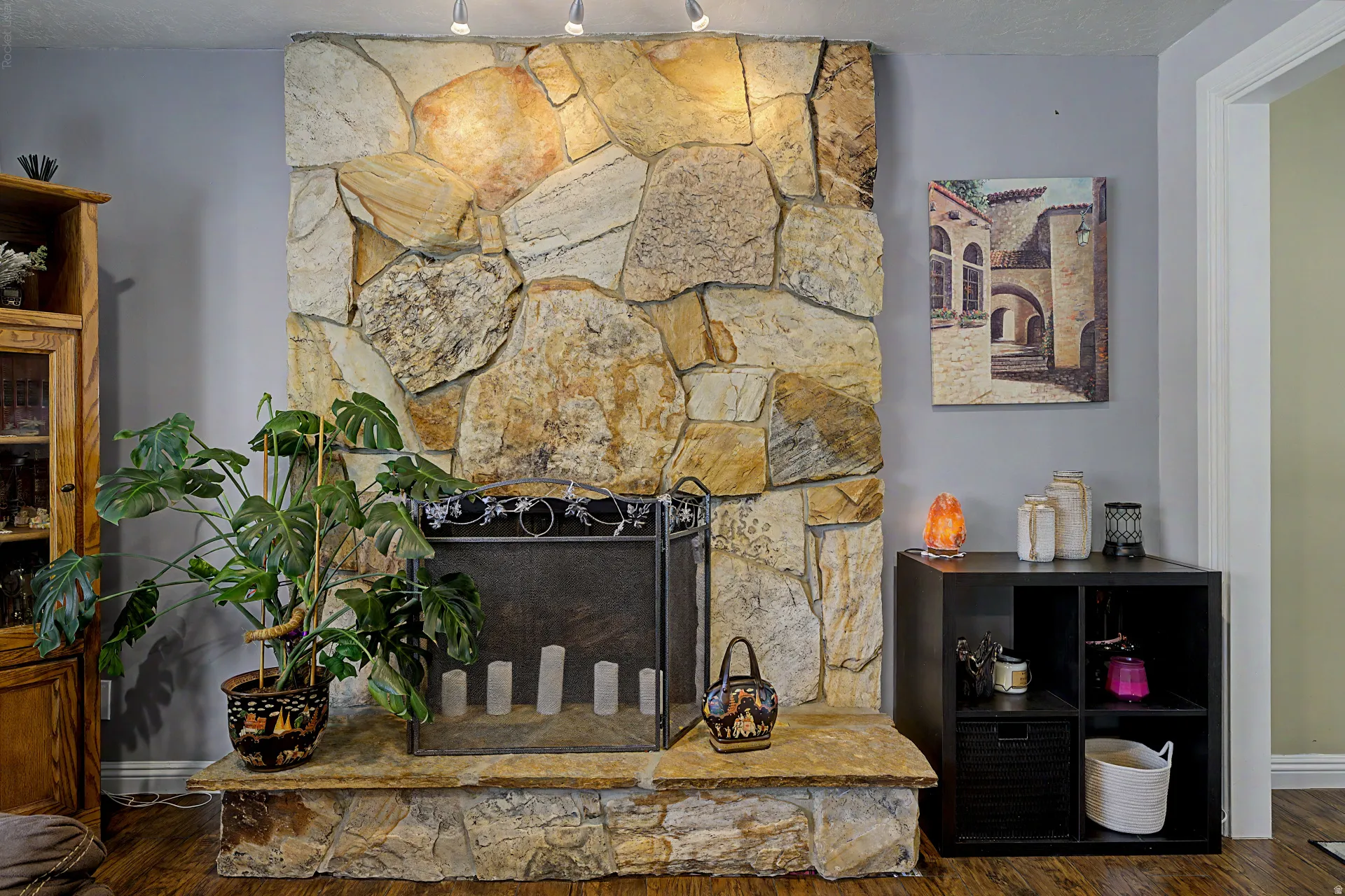 Stone-clad fireplace featuring a hearth and a black metal screen