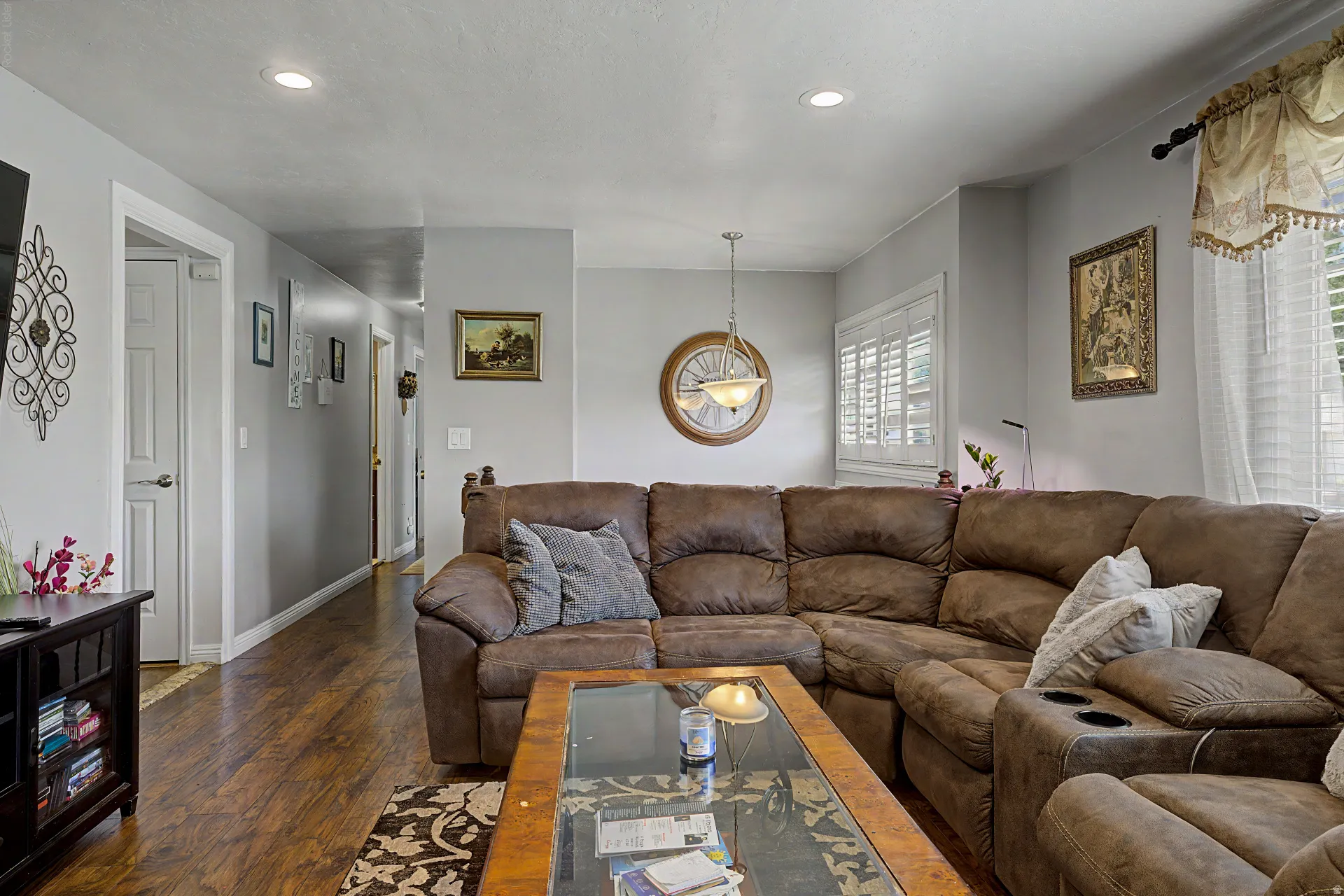 Bright living area featuring wood-finish flooring, recessed lighting, and white plantation shutters