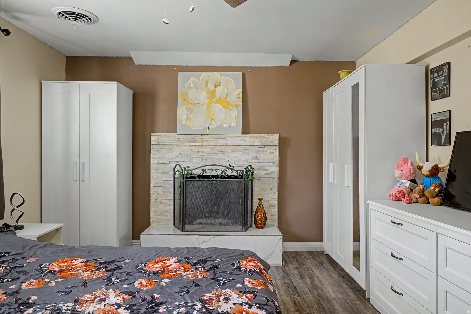 Interior room featuring a stone-clad fireplace with a hearth, wood-finish flooring, and white built-in cabinetry
