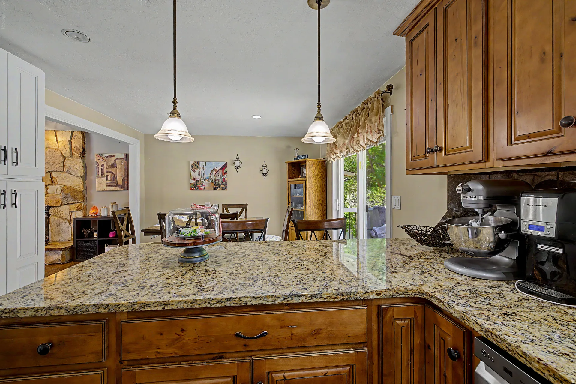 Spacious kitchen island featuring a light-toned granite countertop and two pendant light fixtures