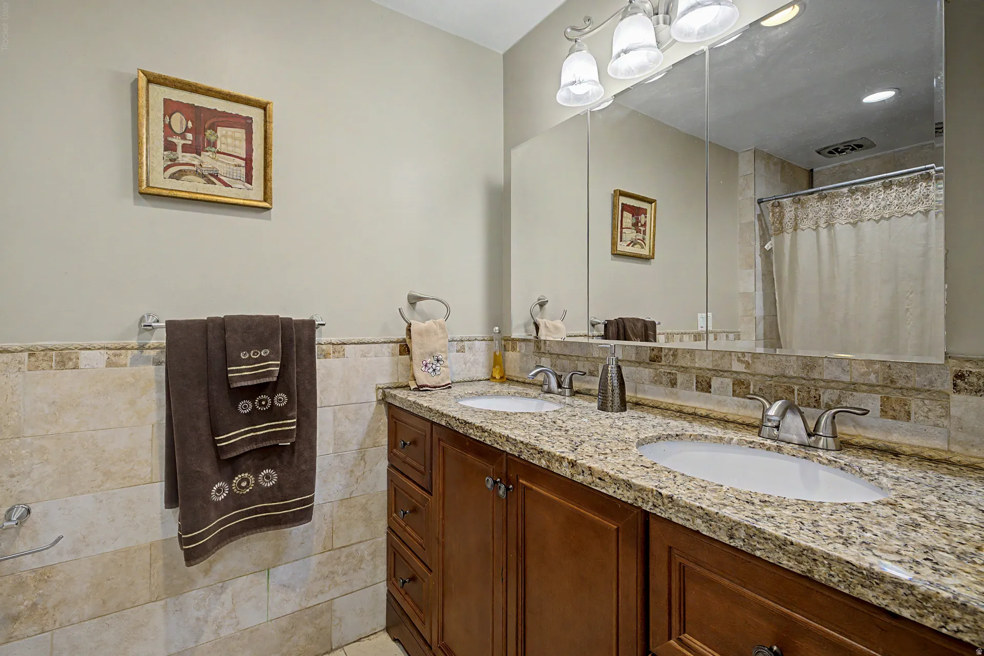 Double vanity with integrated sinks, granite countertop, and wood-finish cabinetry