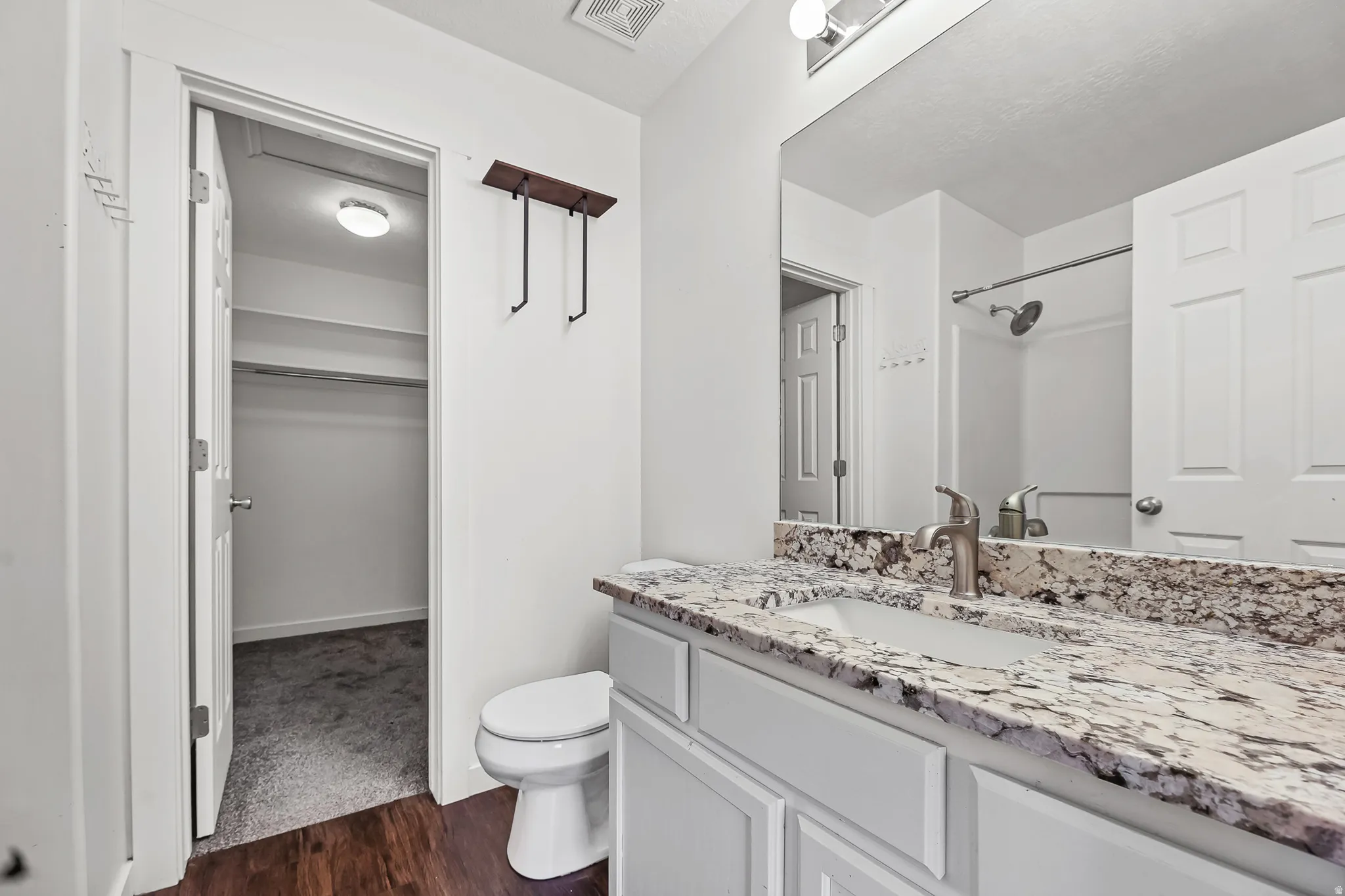 Bathroom featuring a vanity with a light-toned, patterned countertop, an undermount sink, and brushed nickel fixtures