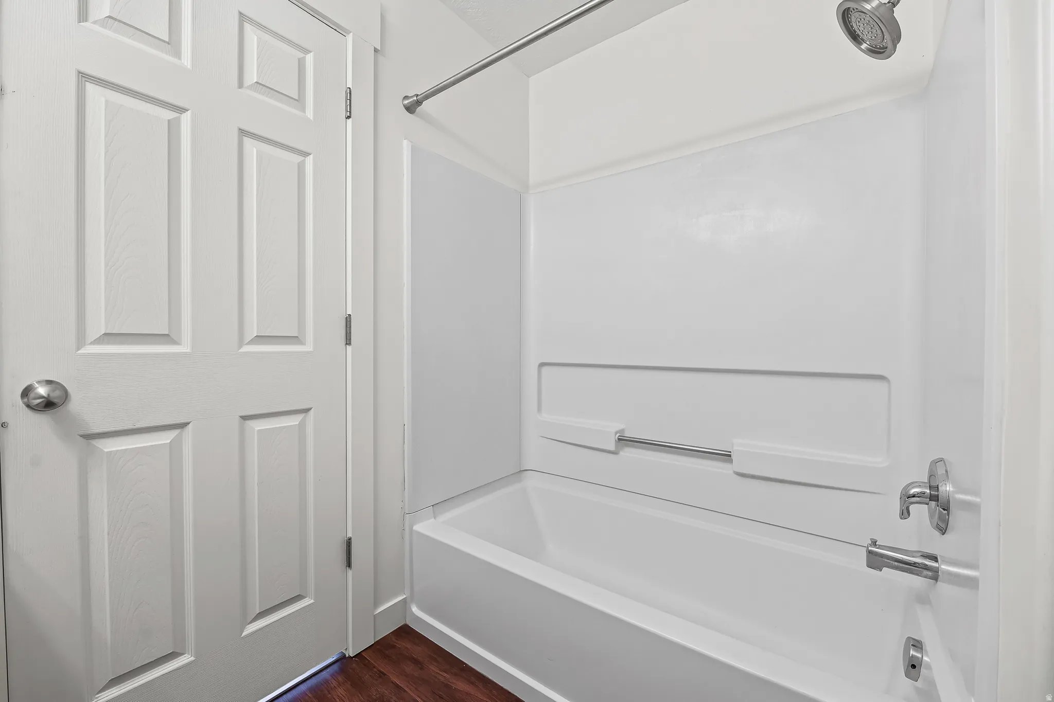 Shower/tub combination with white surround, chrome fixtures, and a white paneled door